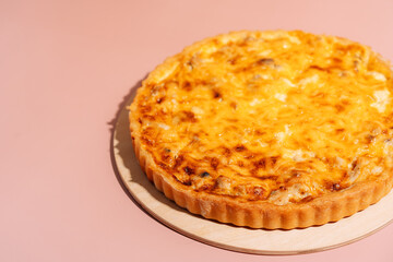 Chicken pie on wooden board on pink background.