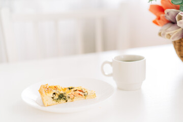Piece of cake on a white plate with a cup of tea.