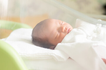 ベビーコットで寝ている新生児