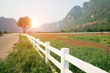 White concrete fence around the agriculture farm or ranching near the complicated mountain with road and sunlight background at the Ban Rai ,Uthai Thani, Thailand.