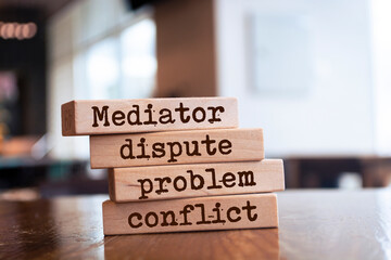 A man holds wooden blocks with the word Mediator, dispute, problem, conflict. Settlement of...