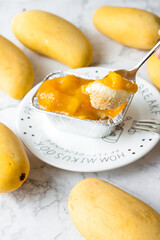 Spoon scooped up the mango cheese pie. Mango Cheese Pie is packaged in a  square aluminum foil in a white plate on a marble table. cake in cafe or bakery shop.