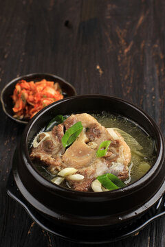 Gori Gomtang  or Korean Beef Oxtail Stew Soup, Served in the Black Korean Bowl with Kimchi and Sliced Green Onion