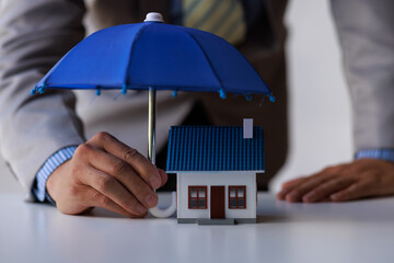 Concept of insurance with an umbrella over a house, and a family