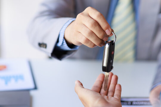 Hand of businessman Smiling car salesman handing over your new car keys, dealership and sales gives the car key concept