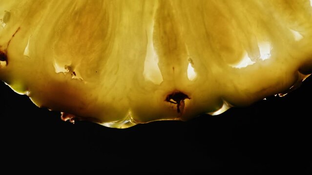 Juicy pineapple slice on black background. Fruit ananas close-up texture, healthy sweet food. Summer refreshment concept.