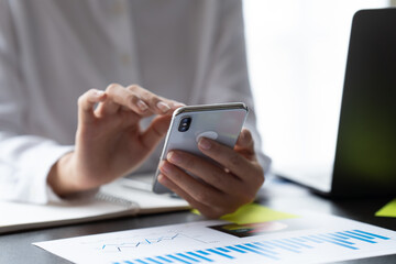 Close up female hands with smartphone, young business crew working with new startup project.