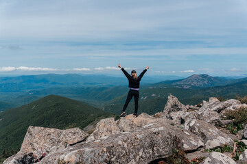 A girl on top of Mount Pidan looks at a beautiful mountain valley in the fog in summer. Travel and tourism. Hiking