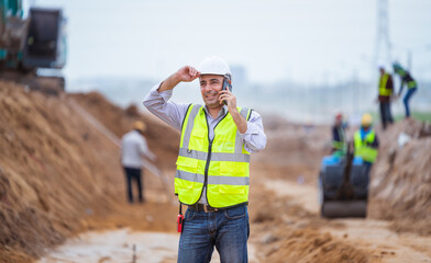 Surveyor engineer wearing safety uniform ,helmet and radio communication with equipment theodolite...