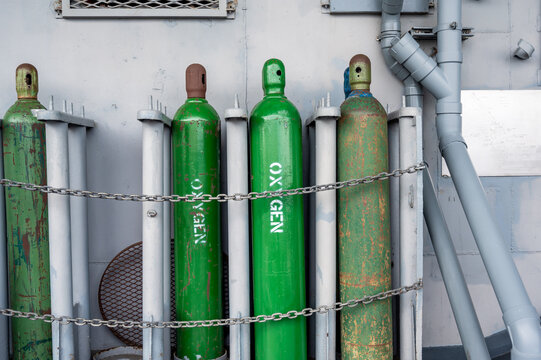 Compressed gas cylinders being stored vertically secured by a metal chain and a metal cap.