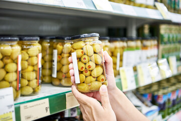 Canned olives in hands buyer in shop