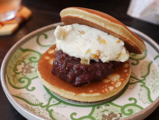 Close up of traditional Japanese Dorayaki in a plate with sweet red bean paste and yuzu cream on table. It’s like the Japanese Kasutera sponge cake, it’s contains honey and mirin