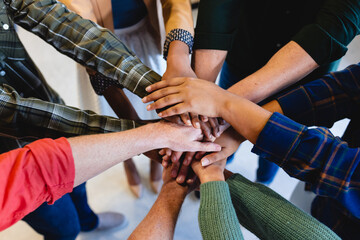High angle view of multiracial fashion designers stacking hands in creative office