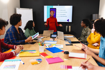 African american businesswoman discussing ideas with app developers in meeting at office