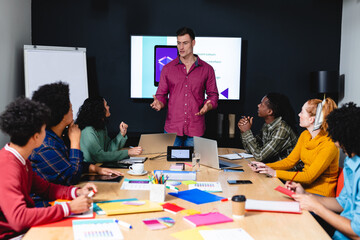 Caucasian businessman discussing ideas with app developers in meeting at office