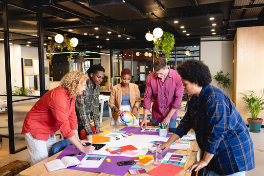 Multiracial design professionals discussing over project in creative office