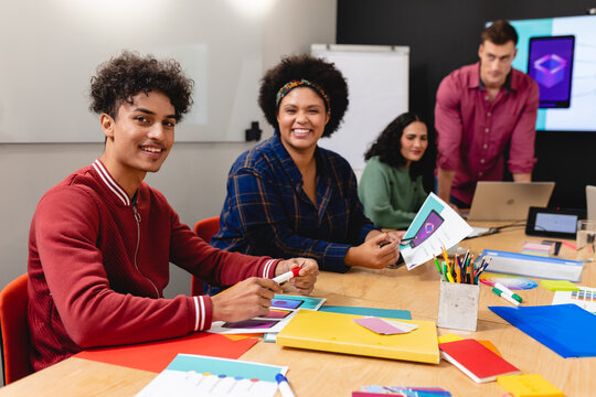 Portrait of smiling biracial app developers with documents in board room