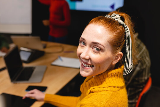 Portrait of smiling caucasian female app developer in board room at office