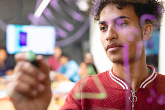 Young biracial male app developer drawing chart on glass in meeting room