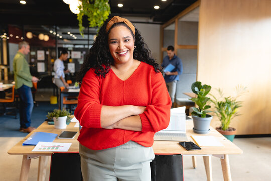 Portrait of confident mid adult biracial creative businesswoman with arms crossed in office