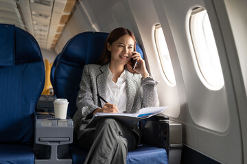 Young attractive and successful business asian woman talking on the phone and working while sitting...