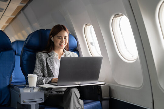 Business Asian Woman Using Laptop While Flying On Airplane Near Window.