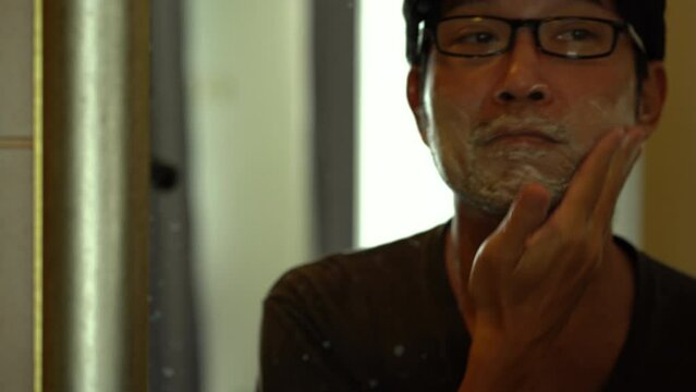 Asian man shaving his beard