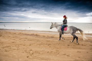 dressing jeans and jacket female horse jokey rides a dappled palfrey along lake