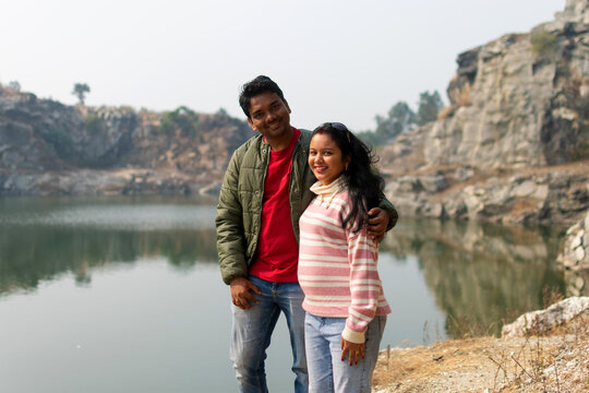 Romantic Indian couple of adults visiting an alpine lake. Tourist in love spending loving moments on a mountains background. Couple, wanderlust and travel concept.