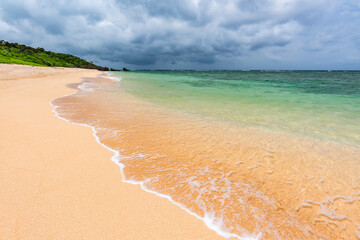Soft aqua blue sea wave over clear sands on a paradise beach.