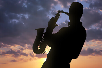 Silhouette of man playing saxophone against beautiful sky at sunset