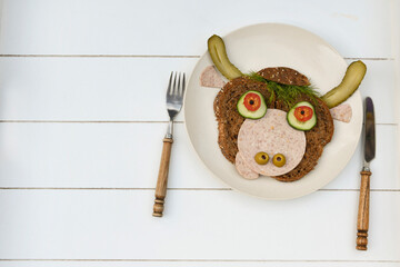 Sandwich iof a cheerful bull made of dark bread, sausages and vegetables 