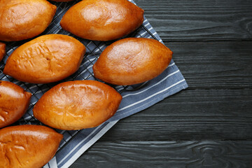 Delicious baked patties on black wooden table, flat lay. Space for text