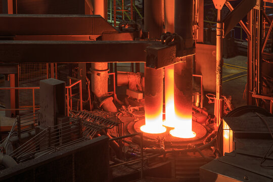 Hot red graphite electrodes in steel mill workshop.