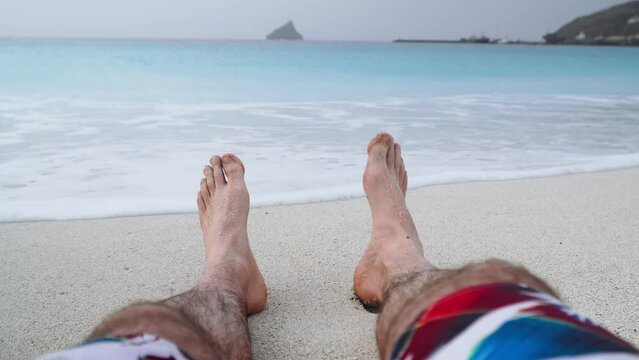Mans feet on sandy beach. Vacation and relaxation concept, beach holidays background. 4k video