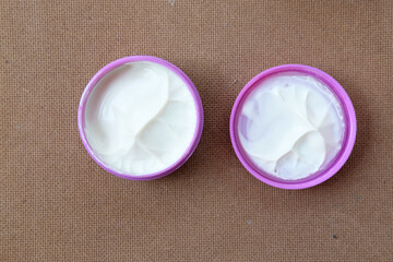A clay, pomade, wax, gel or mousse from round pink box for styling his hair after barbershop hair cut