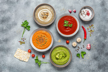 Colored vegetable soups. Set of vegetarian soups. The concept of organic food. Gray concrete background. Top view.