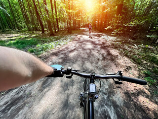 POV photo of riding a bicycle on the forest muddy path. Close up of a bike handlebar with a forest...