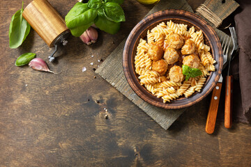 Italian  homemade kitchen. Italian fusilli pasta gluten freewith meat balls in tomato sauce and basil on rustic table. View from above. Copy space.