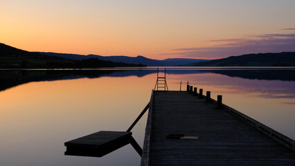 Obraz premium Norwegian lake at sunset with silhouette of pier, Jevnaker, Norway