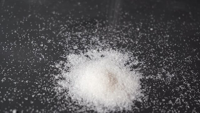 granulated sugar. pouring sugar on a black background.