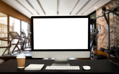 Computer Monitor, Keyboard, coffee cup and Mouse with Blank or White Screen Isolated is on the work table at the fitness gym