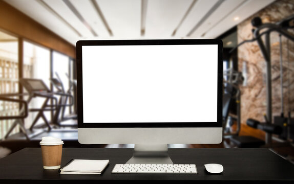 Computer Monitor, Keyboard, coffee cup and Mouse with Blank or White Screen Isolated is on the work table at the fitness gym