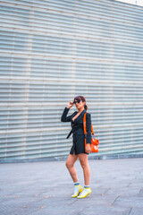 Obraz premium Brunette girl in a fashionable pose in the city with a red bag