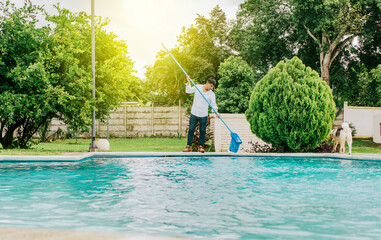 Maintenance person cleaning a swimming pool with skimmer, swimming pool cleaning and maintenance concept. Man cleaning a swimming pool with skimmer