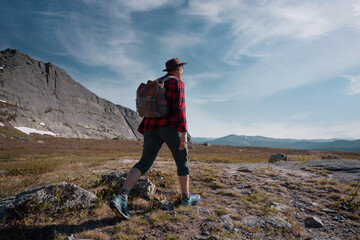 Obraz premium Young traveler tourist dressed as hipster with backpack walks in mountains