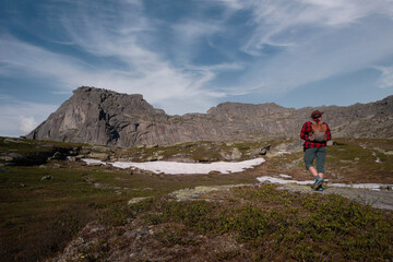Fototapeta premium Young traveler tourist dressed as hipster with backpack walks in mountains