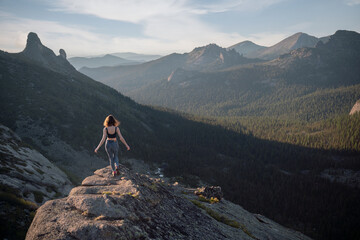 Young girl in sportswear walks along rock in mountains