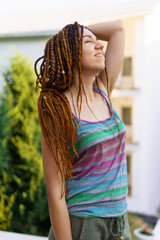 a girl with a dreadlocked hairstyle poses in the summer outdoor