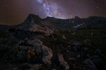 Fototapeta premium Night mountain landscape with milky way and starry sky. Summer among the rocks